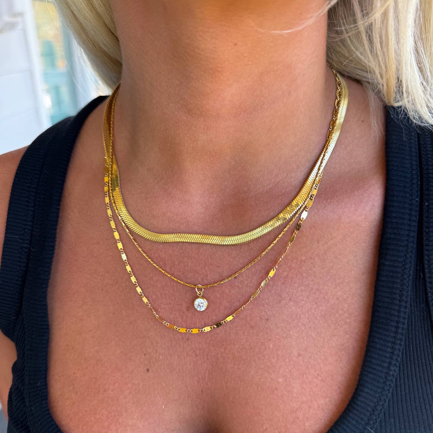 Close-up of a person wearing multiple gold necklaces with a blurred background