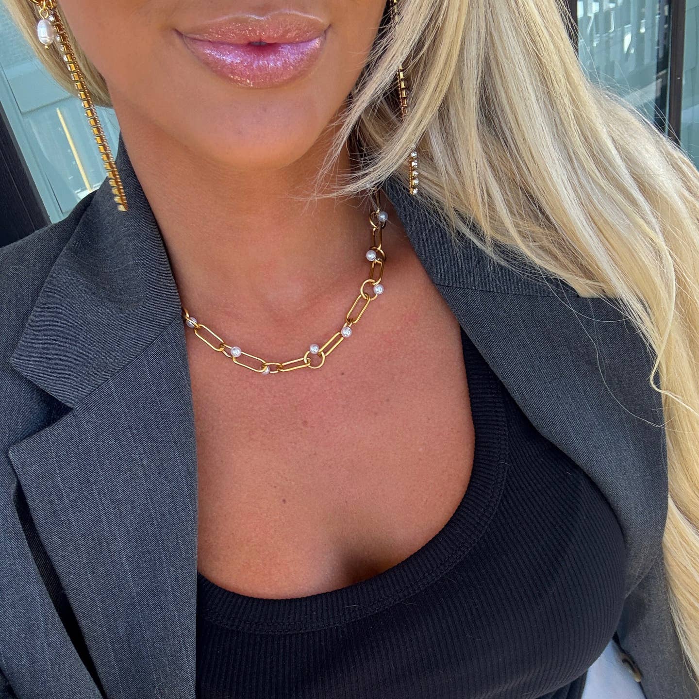 Close-up of a person wearing a gold chain necklace with a blurred background