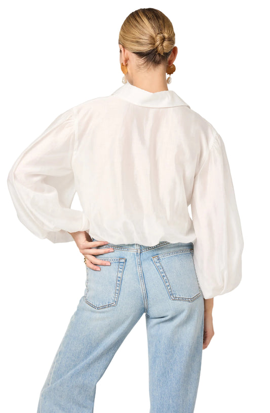 Person wearing a white blouse and light blue jeans on a plain background