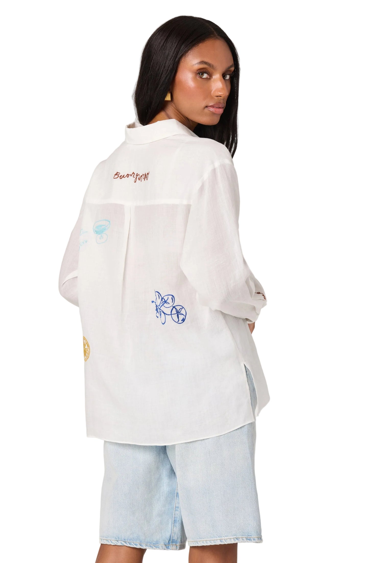 Woman wearing a white embroidered shirt with a plain background