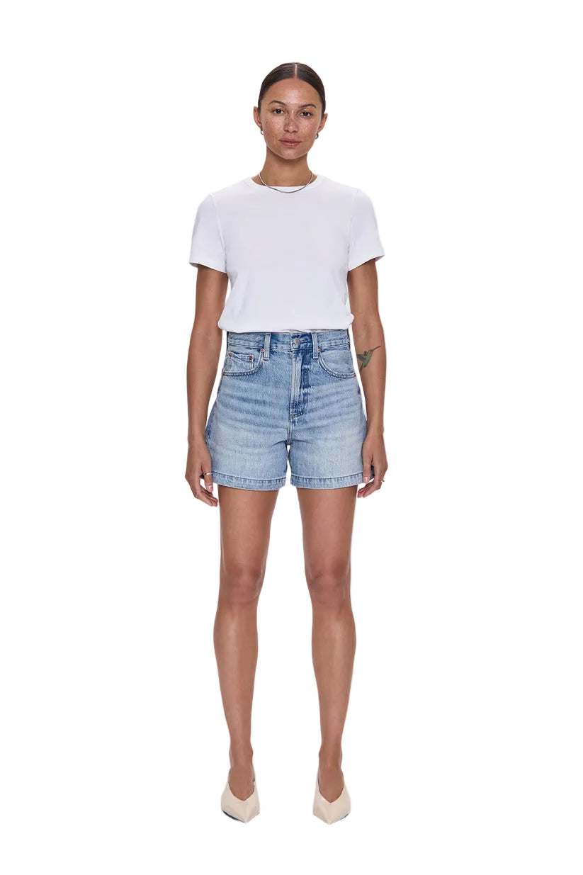 Woman wearing a white t-shirt and denim shorts on a light blue background