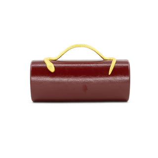 Burgundy clutch with a yellow accent handle, cylindrical shape.