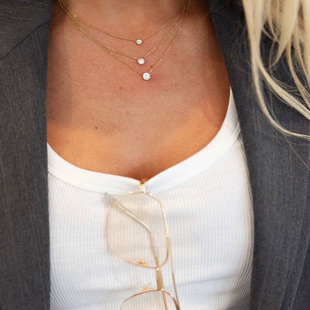 Close-up of a person wearing a gold necklace with small round pendants.