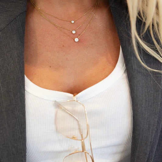 Close-up of a person wearing a gold necklace with small round pendants.