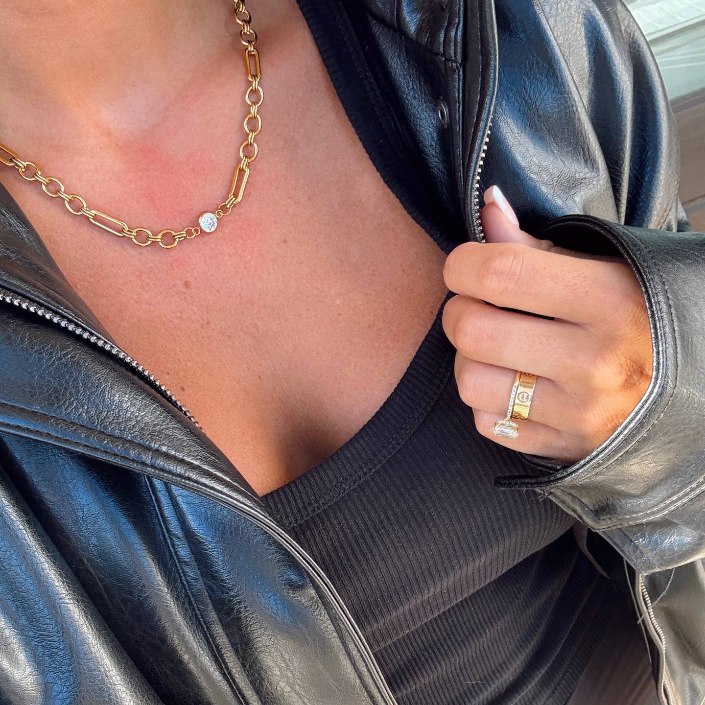 Person wearing a gold necklace and ring, with a close-up on the jewelry.