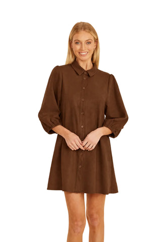 A woman wearing a brown faux suede shirt dress with puff sleeves and button-up front.