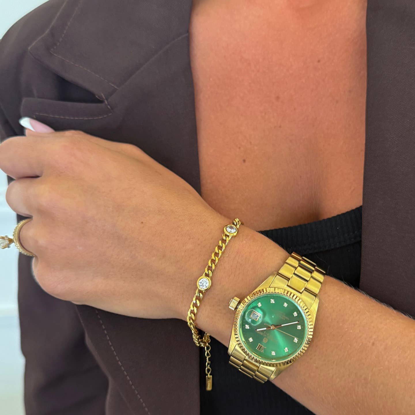 Gold watch and bracelet on a wrist with a blurred background