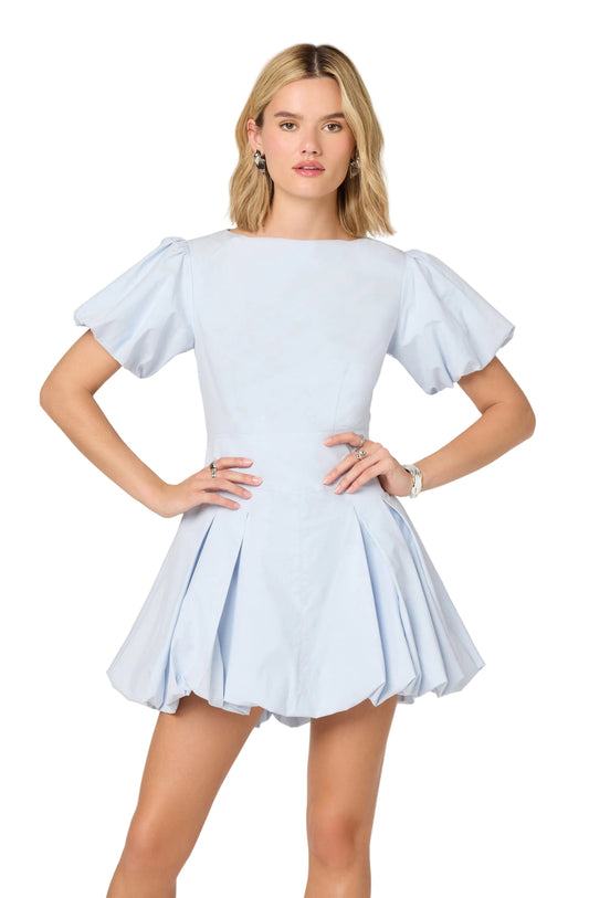 Woman wearing a light blue dress with ruffled sleeves on a white background