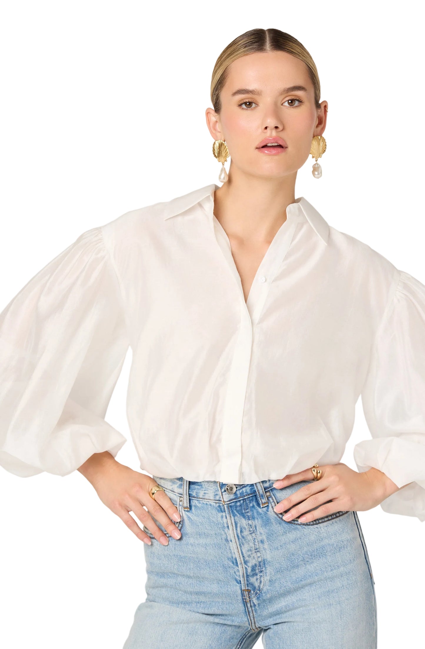 Woman wearing a white blouse and light blue jeans against a white background