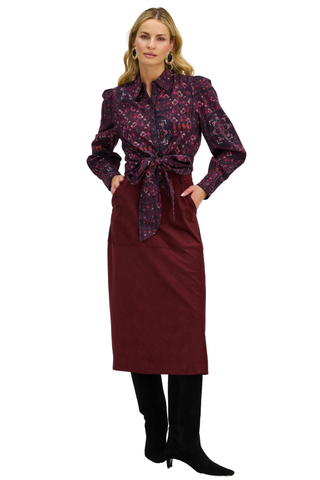 A woman wearing a burgundy scarf print blouse with button-down style and tie waist.