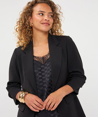 A woman wearing a black 3/4 sleeve blazer with a lapel collar.
