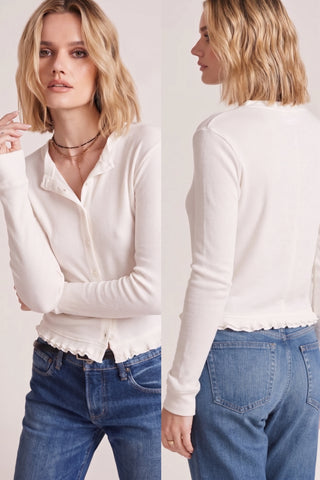Woman wearing a pearl-colored ruffle cardigan with a soft rib texture and ruffled hem, styled with denim jeans.