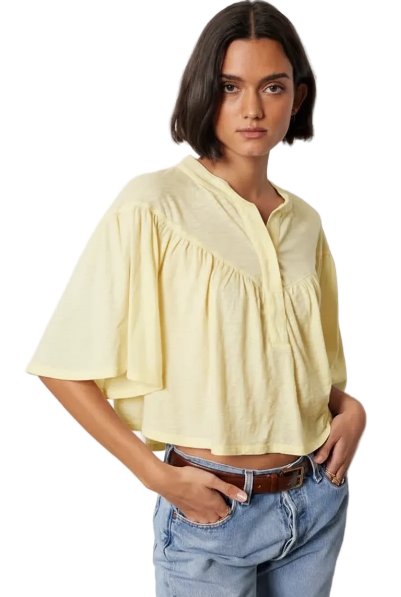 Woman wearing a light yellow blouse and blue jeans against a white background