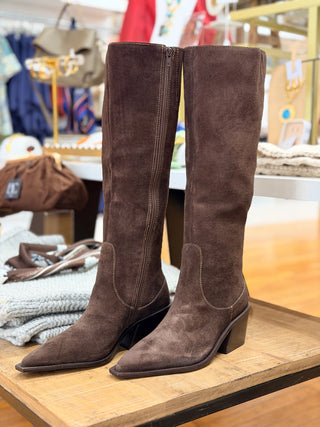 Tall suede boots in a rich espresso color with a side zip and mid heel displayed on a wooden table.