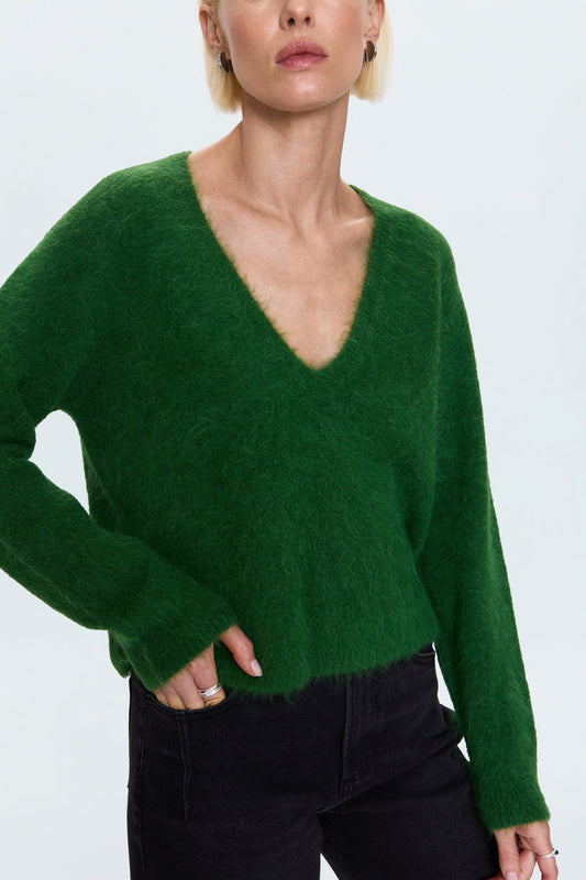 Person wearing a green sweater on a plain background