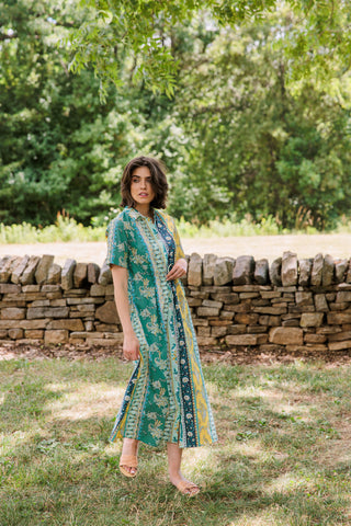 A woman wearing a midi dress with a Paisley Ribbon pattern featuring beige and burgundy colors, a mandarin neckline, and short sleeves.