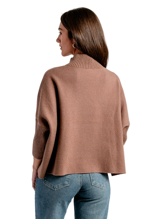 Woman wearing a brown sweater and blue jeans on a white background
