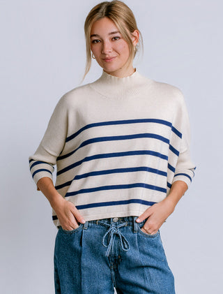 A navy and ecru striped oversized sweater with a ribbed turtleneck and 3/4 sleeves.