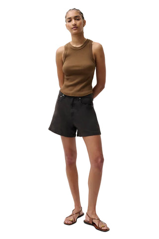 Person wearing a brown sleeveless top and black shorts on a white background