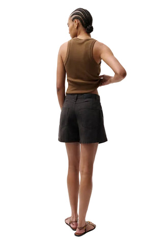 Person wearing a brown sleeveless top and black shorts on a white background