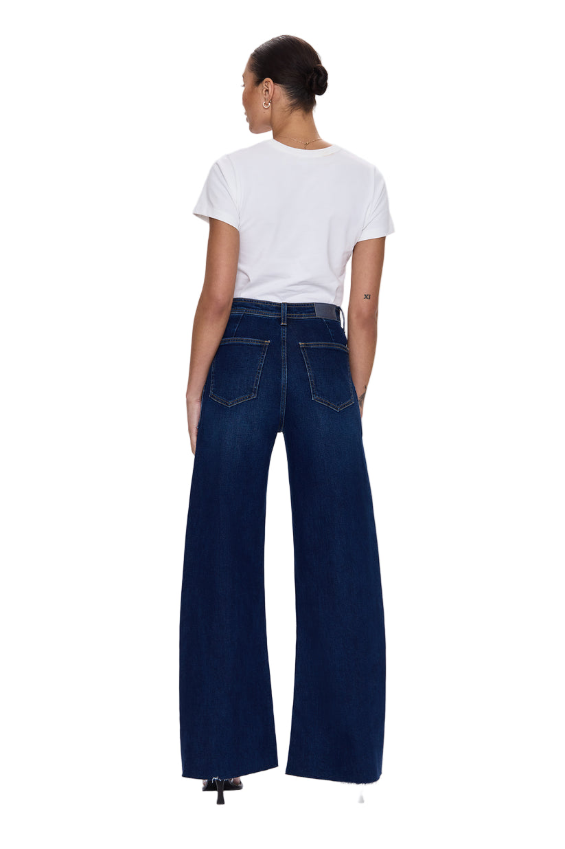 Person wearing blue jeans and a white t-shirt on a light gray background