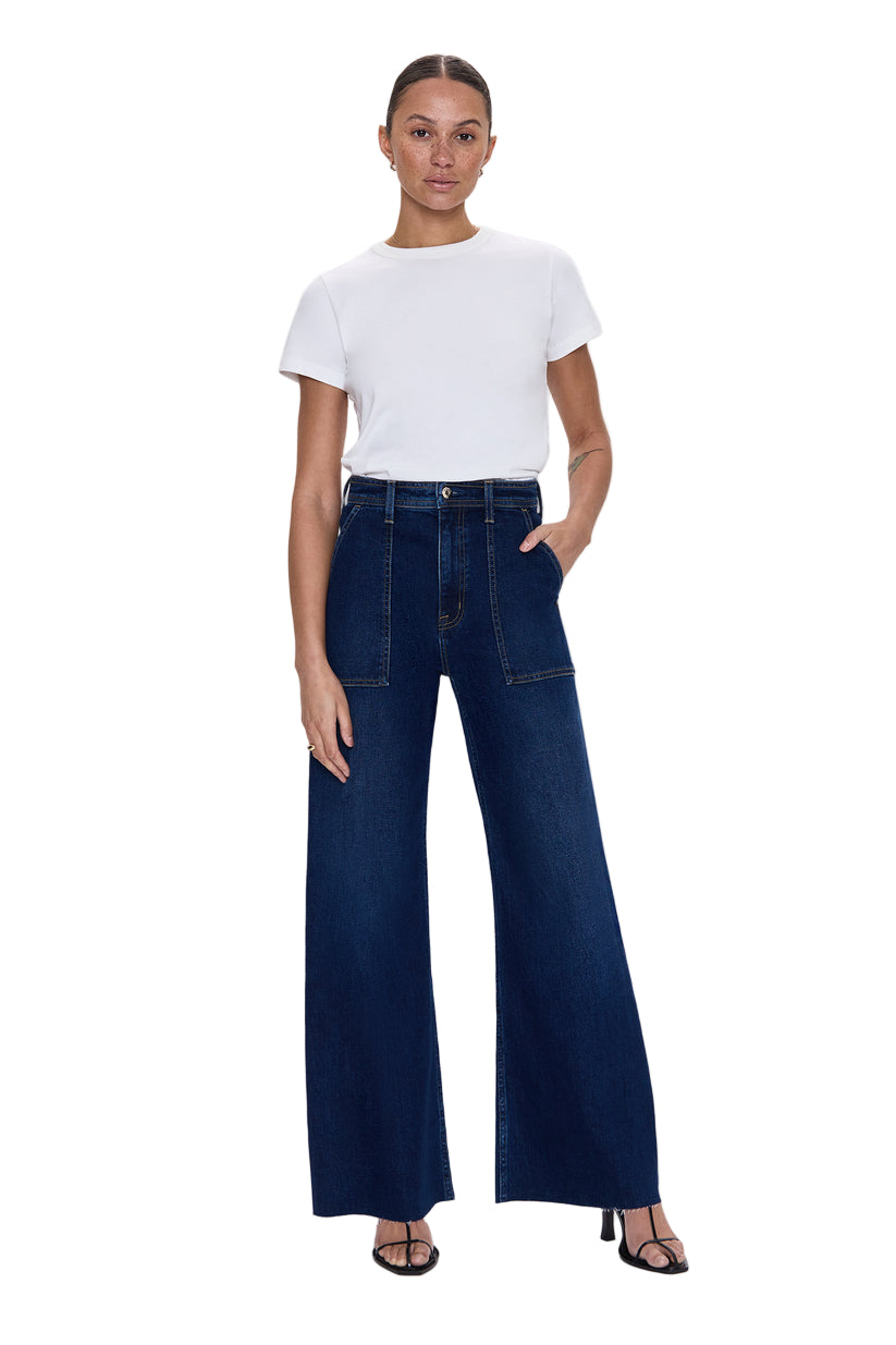 Woman wearing a white t-shirt and dark blue jeans on a light gray background