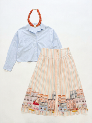 Light blue shirt and striped skirt with cityscape design on a white background