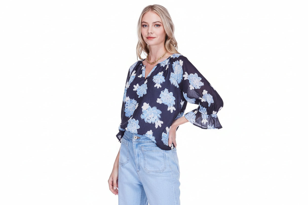 Woman wearing a navy blue blouse with blue floral pattern on a white background