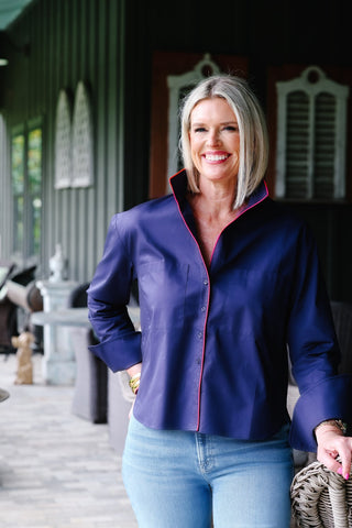 A woman wearing a navy blue shirt with hot pink piping, featuring front patch pockets and long sleeves.